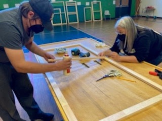 Volunteers of all ages work together to assemble insulating window inserts