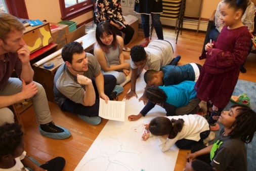 Youth drawing and speaking with a facilitator at a meeting