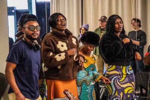 Member of the Congolese Choir singing during an All the Rivers rehearsal Members of the Congolese Choir dancing and singing wearing colorful traditional African clothing at an All The Rivers rehearsal