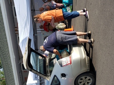 Volunteers place groceries in participant vehicle