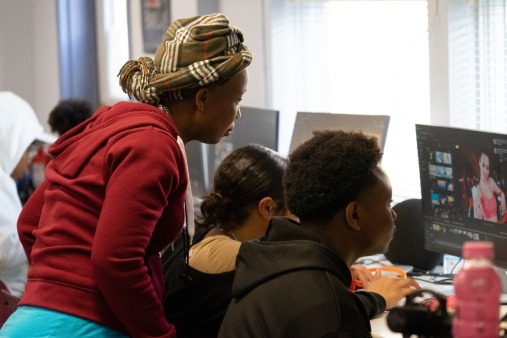 JustFlix coordinator looking over shoulder of youth participants