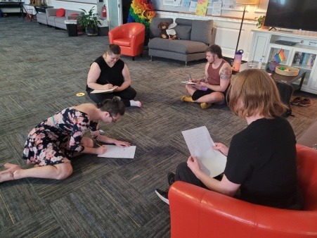 Image features 4 individuals writing poetry at a poetic movements workshop