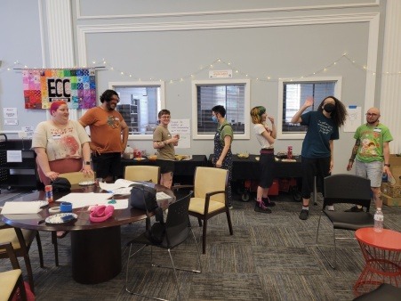Image features 7 individuals at an art swap event playing art party games