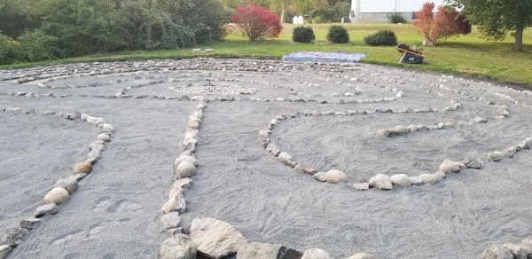 Stone dust spread over the weed barrier and rocks replaced to line the walkway; rocks were from community members bringing from their home to be part of this 