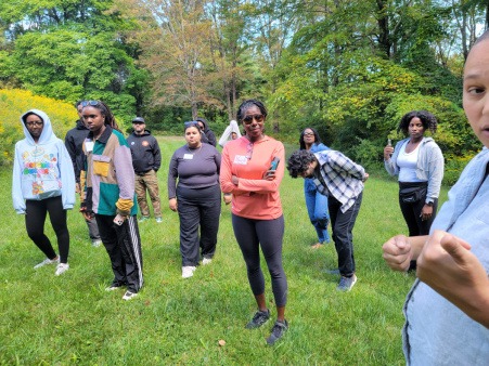 A group gathers around each other on the grass at one of the Our Fire Collective Retreats