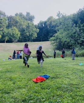 During youth summer soccer practice, the atmosphere becomes lively and exciting when kids are enthusiastic about joining a particular team. On the sun-drenched grass, the coach carefully laid out two vibrant pinnies: one a bright, cheerful orange and the other a striking blue. As the young players eagerly raced toward the field, the first to reach the pinnies would secure their spot on the team, creating a spirited and competitive scene that set the tone for the day's practice.