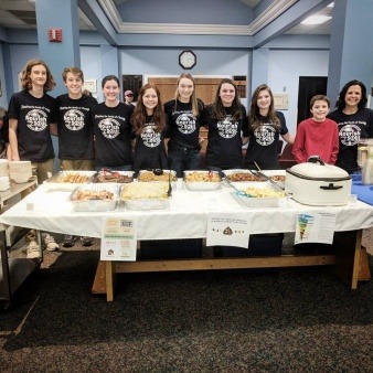 From The Ground UP leaders stand at the serving table for a free community dinner highlighting the use of rescued food