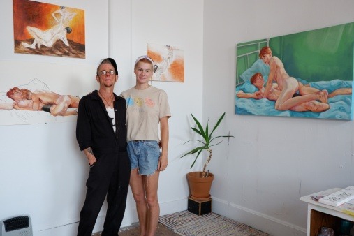 Artists Rboots Scherzter and Hale Linnet stand in front of their Self Portraits for Survival Exhibition of portrait paintings