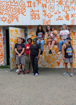 Group of diverse people, especially young people posing before a primed wall with doodle method for mural making
