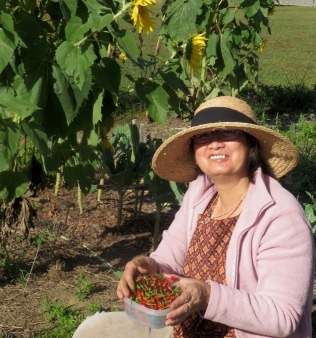 Woman seated by sunflowers holding a bowl of berries