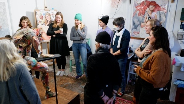 A crowd of people gather in an art space to look at a sculpture