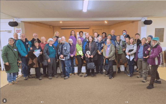 Image of a group of many people posing for a photo smiling inside of a room after a training for Community Relief Fund
