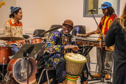 All the Rivers percussionists, Daiki Hirano, Assane Coly, and Ousmane Camara, during a 2026 All the Rivers rehearsal All the Rivers percussionists, including Daiki Hirano, Assane Coly, and Ousmane Camara, wearing colorful clothing while drumming and playing the balaphone during an All the Rivers rehearsal