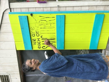 Saadia painting our working agreements onto the doors of the kitchen