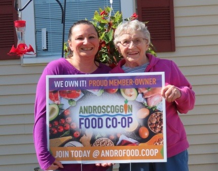 Two women holding sign saying "Proud Member-Owners"