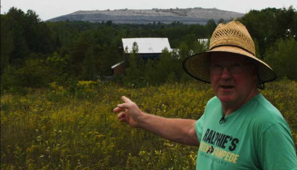 DWME member points out his view of Juniper Ridge Landfill Man points to huge landfill beyond farmland