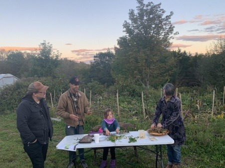 Community member Marty Dagoberto and his daughter roll up fresh wild leaf grape leaf dolmas at Foxtrot Herb Farm