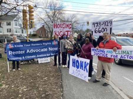 Members of Housing and Climate Justice for Acton hold signs and banners as part of a renters rights Stand Out in March 2022.
