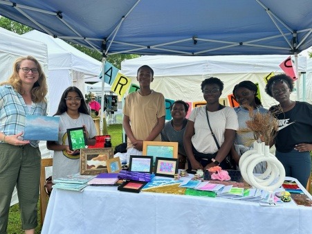 Artepreneurs Youth participants standing behind booth at West Medford Open Studios festival.