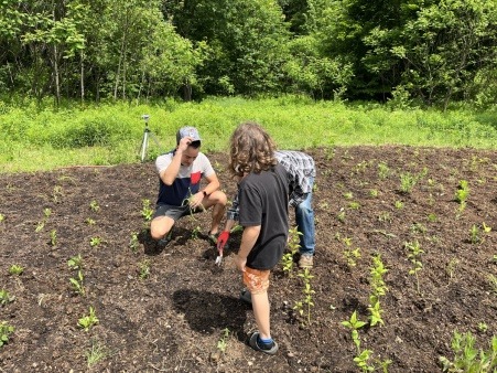 Three people planting flowers. One is kneeling. 