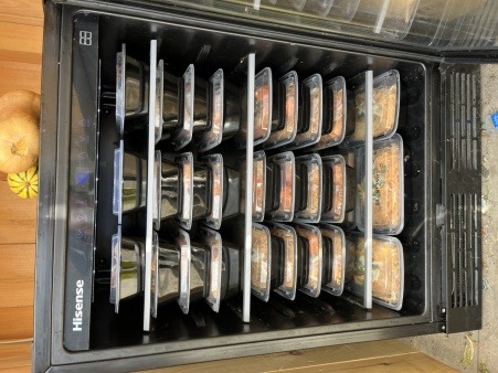 A small fridge full of takeout containers 