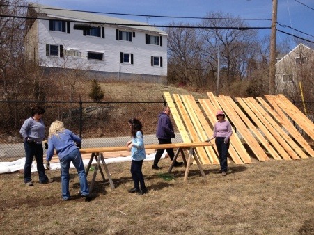 Volunteers preparing wood for garden boxes