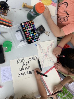 A photo taken from above of Joy Truck 4H Kids designing the poster for the Kids Only Art Show