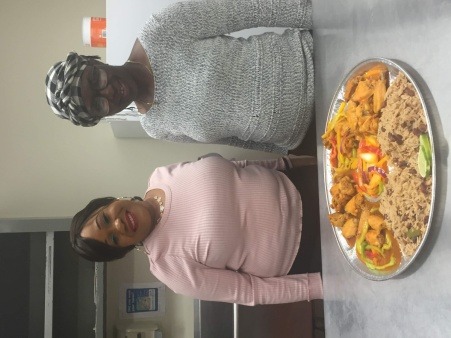 Resident coordinators pose with dish of chicken in red sauce