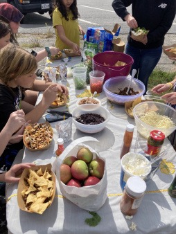 A photo taken from above of youth enjoying tacos, apples and juice during lunch.