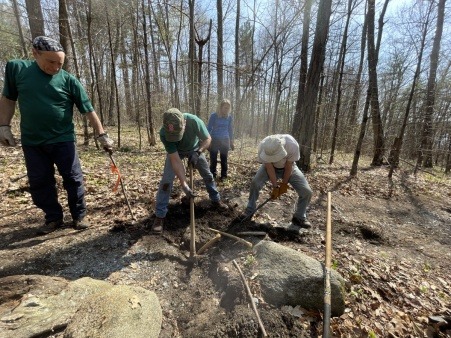 A professional trail builders teaches volunteers how to install water bars to divert water off a friendly trail.