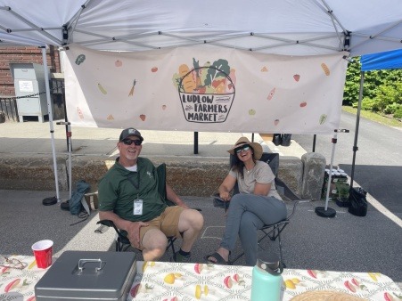 Volunteers Larry Dockum and Heather Tucker (left to right) smiling at LFM's welcome booth.