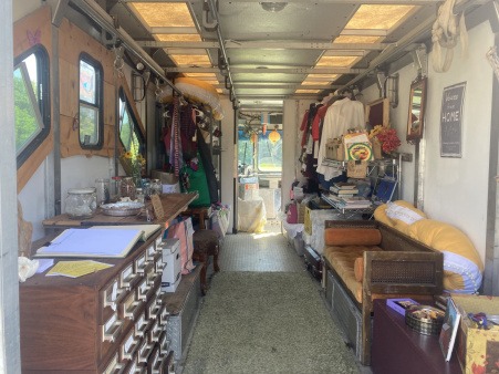 A photo showing the interior of the Joy Truck, a long space with library card catalog medicine and personal hygeine cabinet, a couch, materials and the clothing rack.