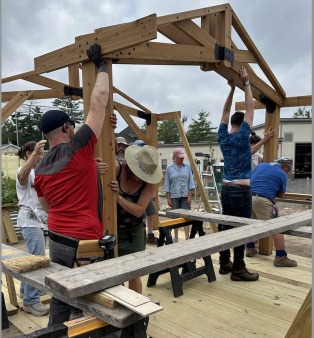 BCG volunteers raise the garden pavilion together—an example of the shared effort and community capacity that have built the garden from the beginning. Community Building the Pavilion