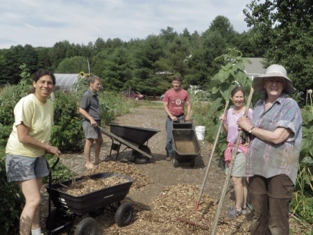 Group of people holding gardening tools at community garden plots