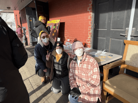 Three Clean Air Club BTV Members pose in masks in front of their table at the Barre Queer Craft Fair