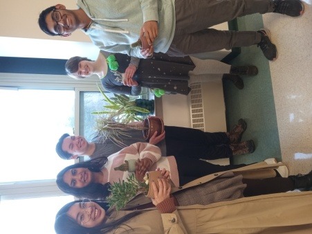 5 vibrantly smiling high schoolers hold potted plants
