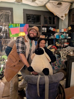 Two people smiling with their completed project from at a halloween mending workshop 