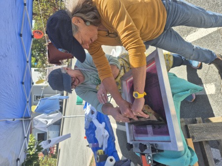 This image is of two board member who were leading a screen printing program at the market. 