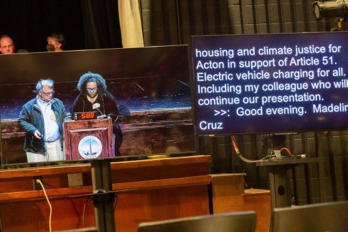 Two members of Housing and Climate Justice for Acton present the group's EV Charging for All item at Acton's Town Meeting in May 2022.