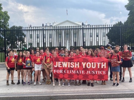 JYCM Leadership Board members staging a protest in front of the White House with a red banner reading “Jewish Youth for Climate Justice”