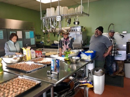 A team of volunteers are hard at work preparing food for a community meal.