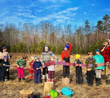 Picture of a group of kids holding a woven art piece