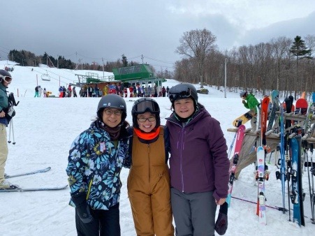Three Asian Americans smiling in ski gear at ski mountain