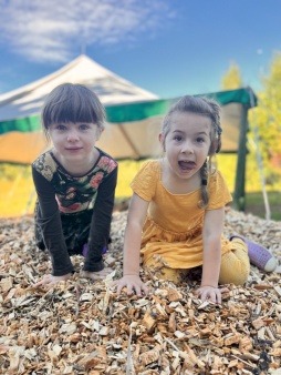 Picture of two children being silly on top of a wood chip pile