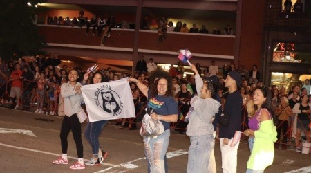 Organizers from the Milagros Project of Rhode Island hold an organizational flag as they walk in a parade.